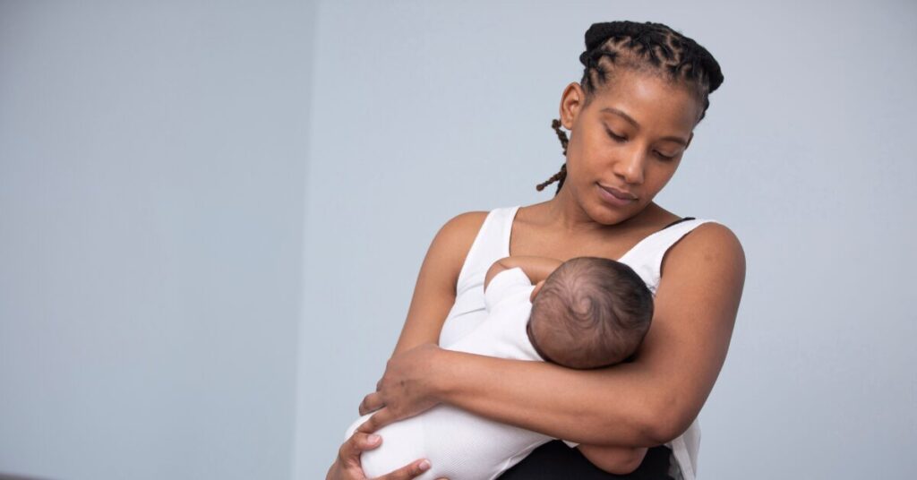 Mãe em contato pele a pele com o bebê durante a amamentação, criando vínculo emocional por meio do toque e do olhar